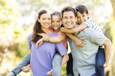 Happy children enjoying piggyback ride on parents
